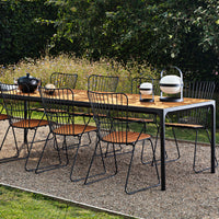 Stylish outdoor dining set featuring a wooden tabletop, black wire chairs, and a modern ceramic lantern. Perfectly balanced colors.
