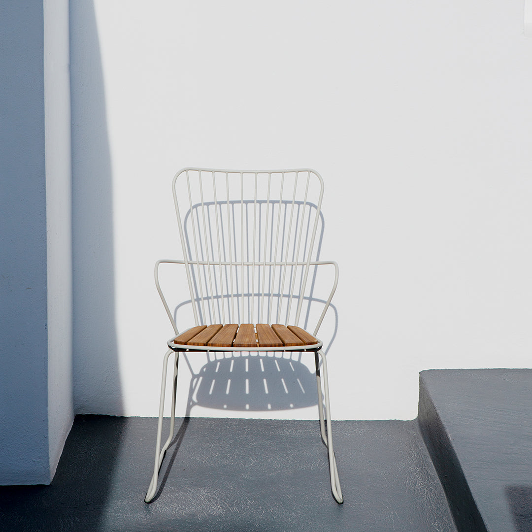 White wire chair with a brown wooden seat, featuring a minimalist design against a light gray background.