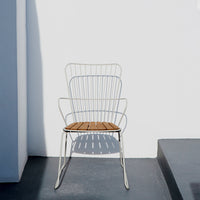 White wire chair with a brown wooden seat, featuring a minimalist design against a light gray background.