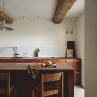 "Warm wood tones with rustic beams, soft neutral walls, and minimalist decor create a cozy kitchen ambiance."