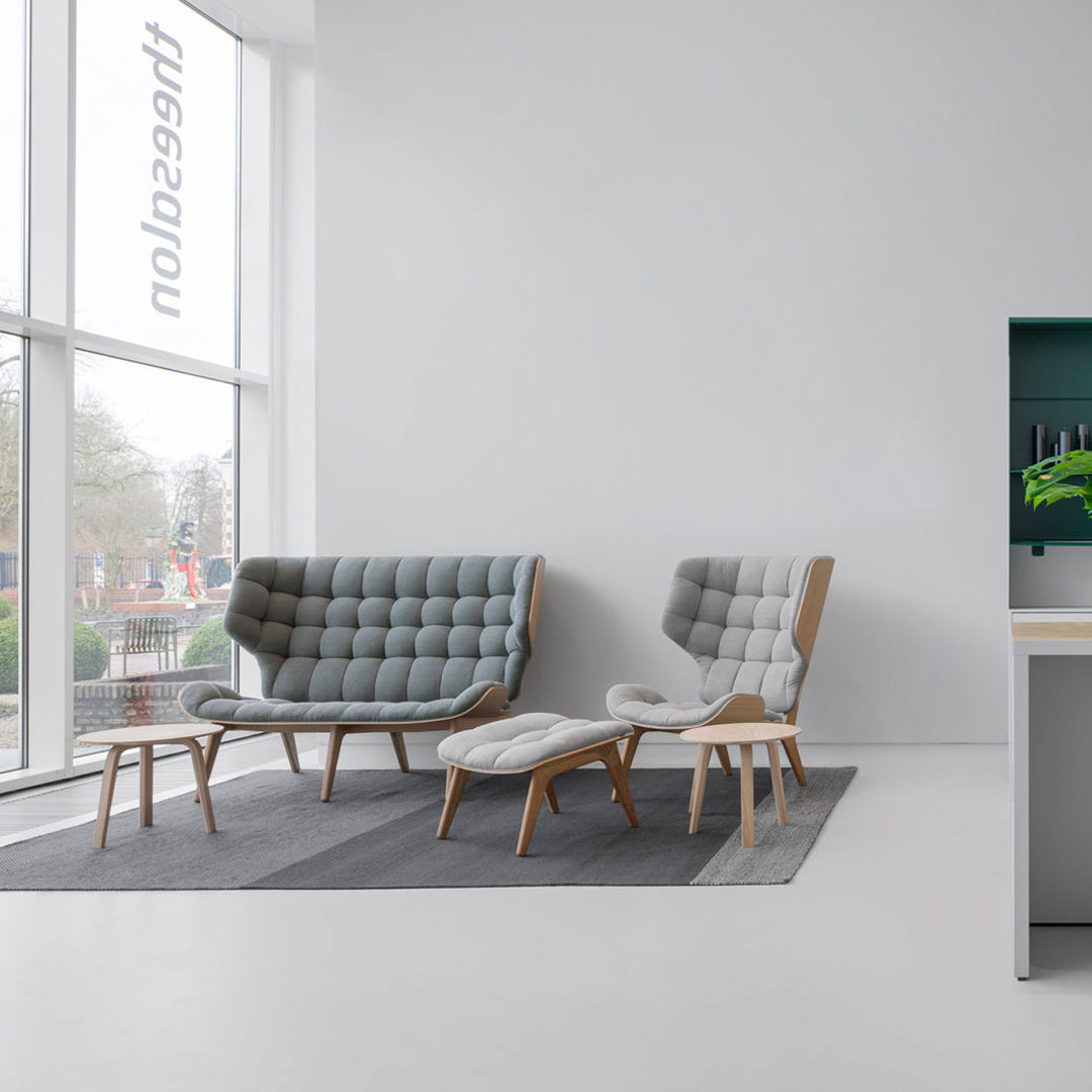 "Modern gray tufted furniture set with light wooden legs, complemented by a textured gray rug."