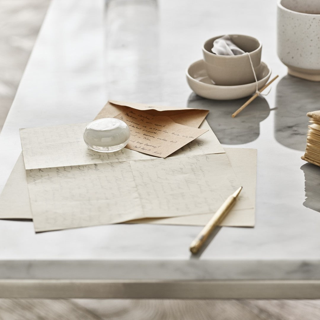 "Elegant neutral tones and soft textures with patterned papers and minimalist ceramic items on a marble surface."