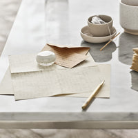 Neutral-toned stationery and ceramic bowls on a glossy marble table, featuring soft textures and subtle patterns.