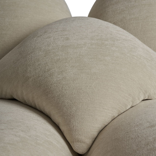 Soft beige decorative pillows featuring a smooth, textured fabric in a layered arrangement.