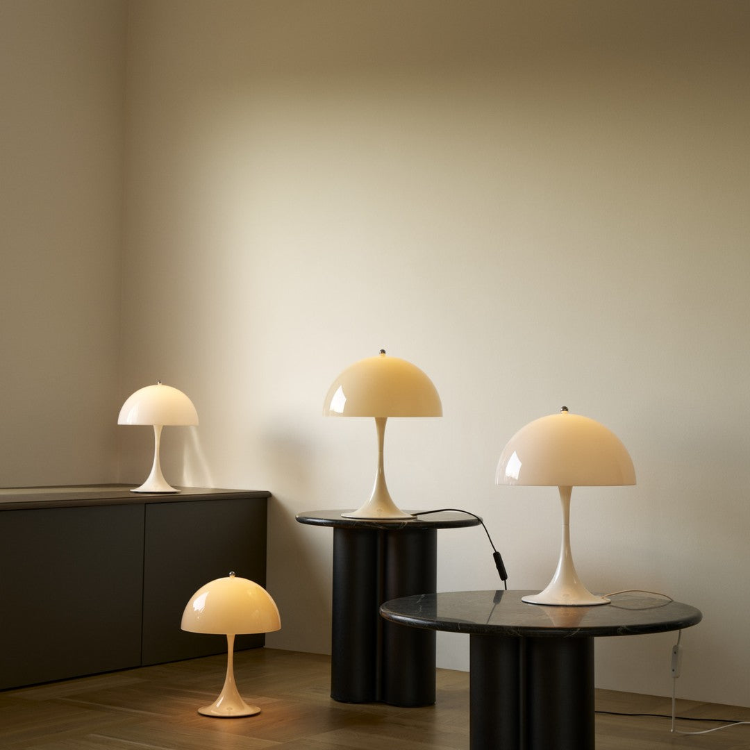 Four Panthella table lamps on black stands against a beige wall.
