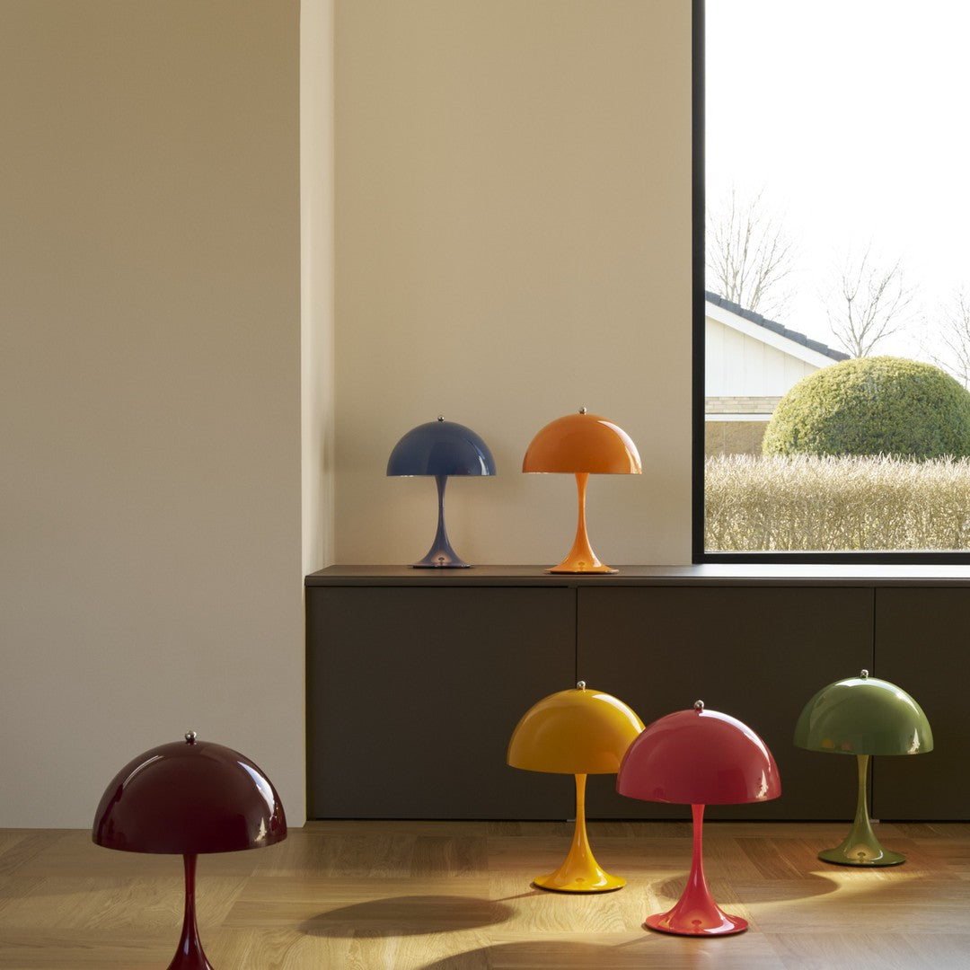 Colorful Panthella table lamps on a wooden floor with a neutral wall and window in the background