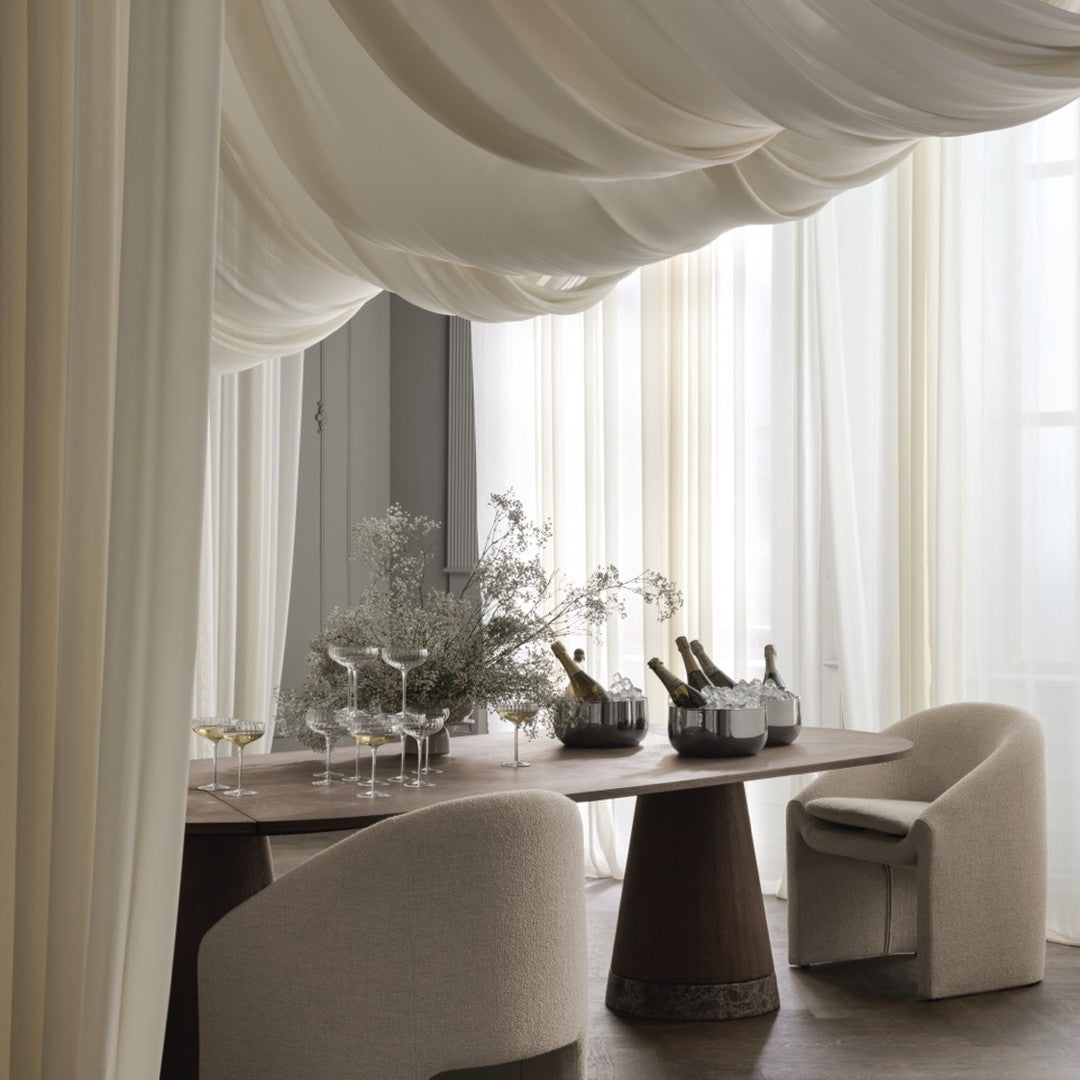 Elegant cream drapes with soft, flowing patterns, complemented by neutral-toned furniture and a wooden dining table.