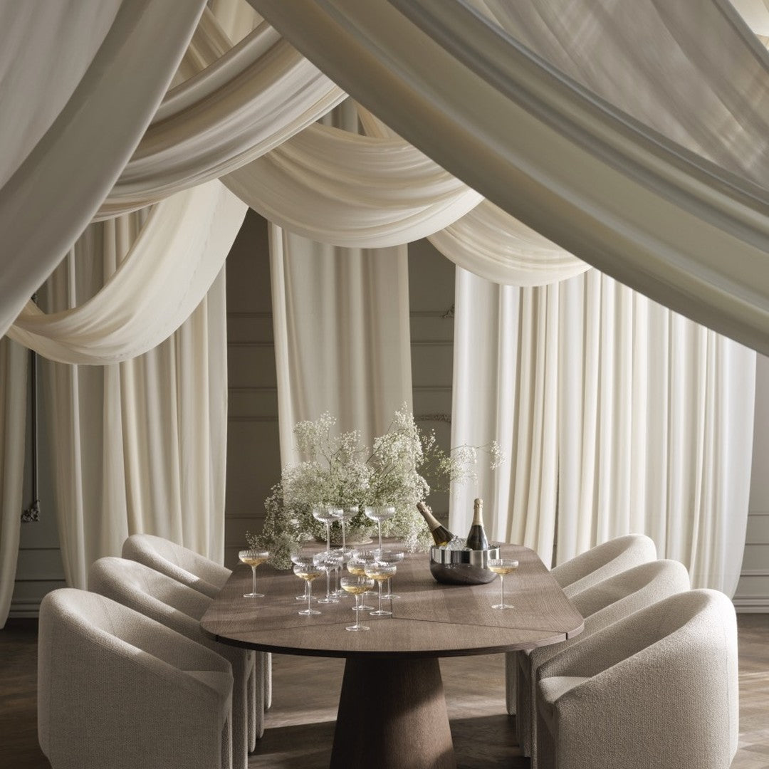 Elegant beige drapes with soft, flowing patterns create a warm, inviting atmosphere around a modern wooden dining table.