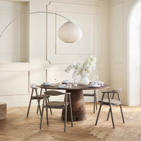 Modern round wooden table with gray chairs, neutral tones, and soft white floral decor, set in an elegant light space.