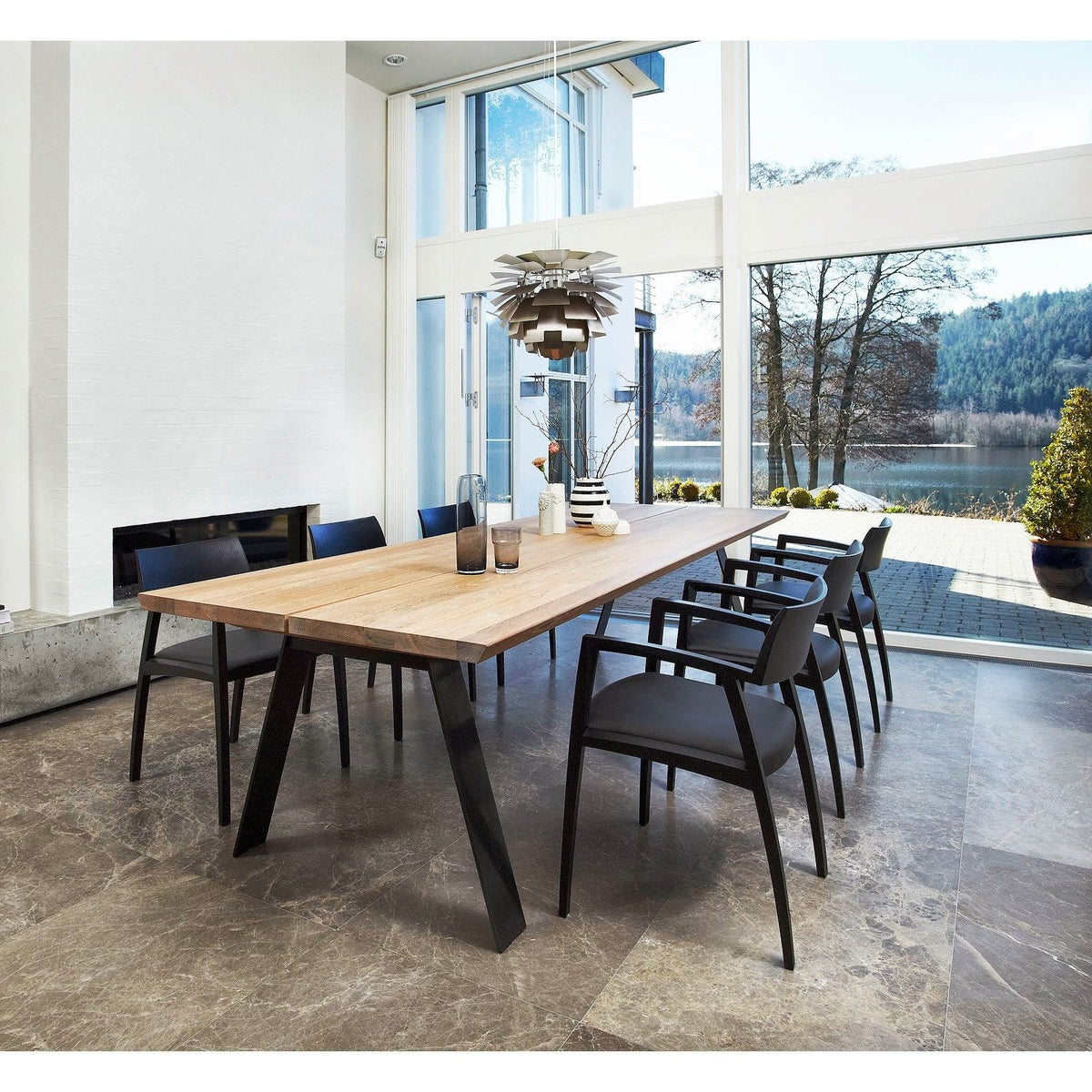 Natural wood table with sleek black legs, surrounded by minimalist black chairs, set against a bright, airy backdrop.