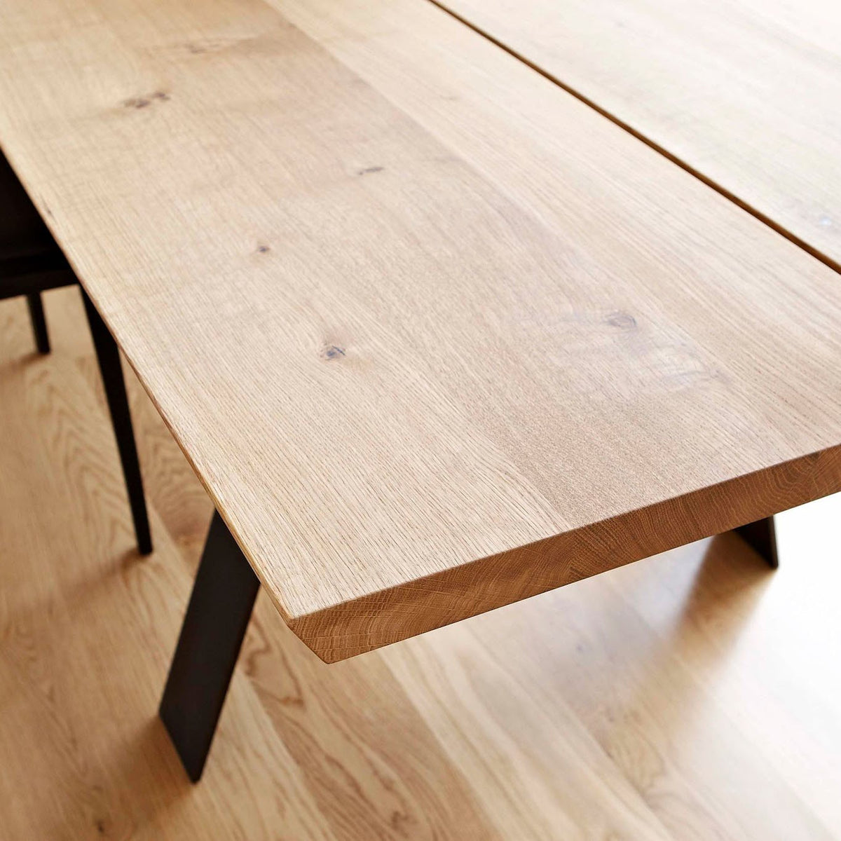 Natural wood table with a light oak finish and smooth, warm grain, set against a light wooden floor.