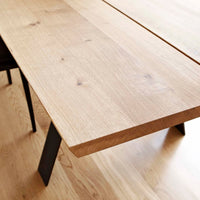 Natural wood table with a light oak finish and smooth, warm grain, set against a light wooden floor.