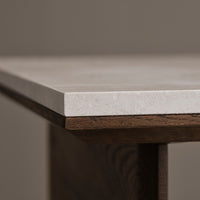 Close-up of a sleek white stone tabletop with a smooth finish, set against rich brown wooden edges.