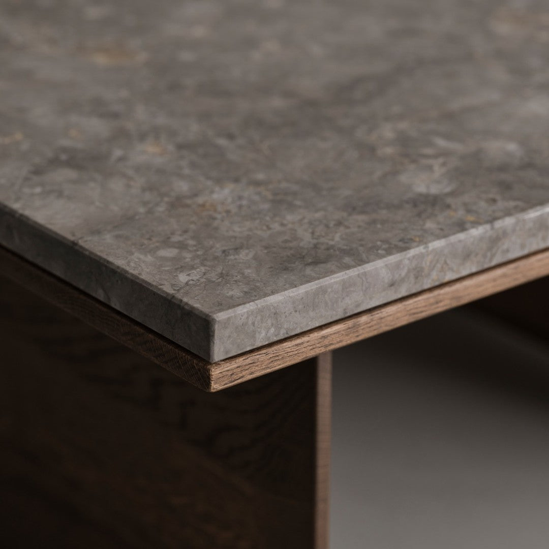 Close-up of a textured gray stone countertop with warm brown wood edges, showcasing a modern and natural pattern.