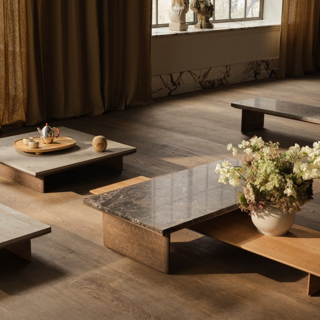 Minimalist wooden coffee tables with marble tops in earthy tones, complemented by neutral curtains and floral arrangements.