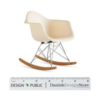 Cream-colored rocking chair with smooth curves and a minimalist design, featuring natural wood rockers and metallic legs.