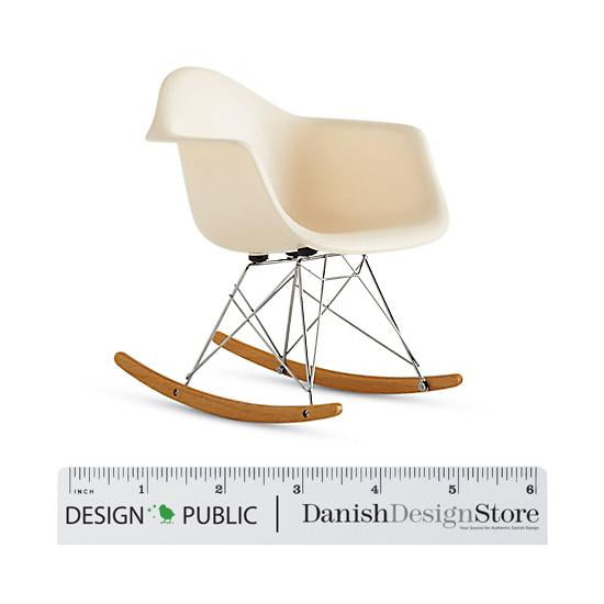 Cream-colored rocking chair with smooth curves and a minimalist design, featuring natural wood rockers and metallic legs.