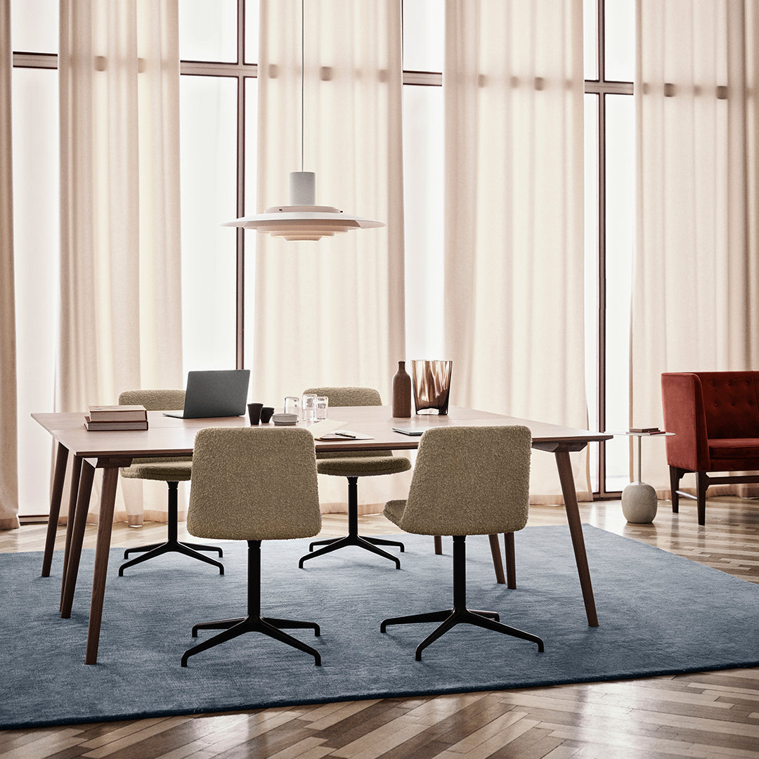 Modern dining set with beige chairs, a light wood table, and a blue textured rug, complemented by warm, neutral curtains.