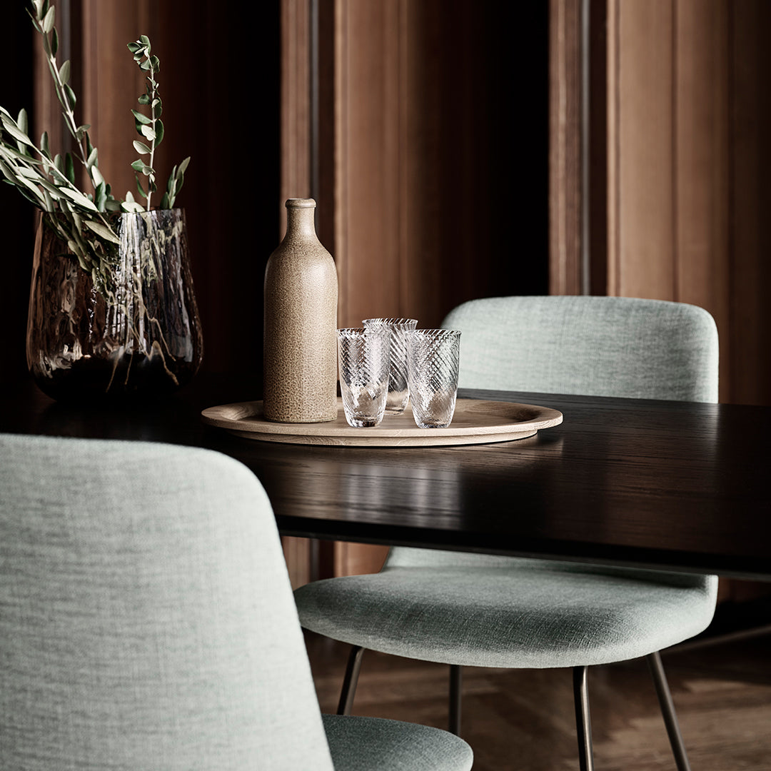 Stylish light blue chairs, natural wooden table, and earthy tones of ceramic and glass decor. Elegant minimalism.