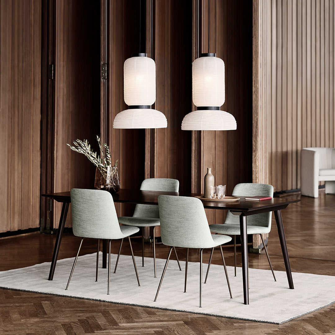 Modern dining room featuring mint green chairs, a dark wood table, and soft white pendant lights against a textured backdrop.