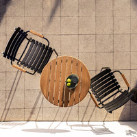 Black slatted chairs paired with a round wooden table, set on a light gray tiled surface. Perfect for outdoor living.