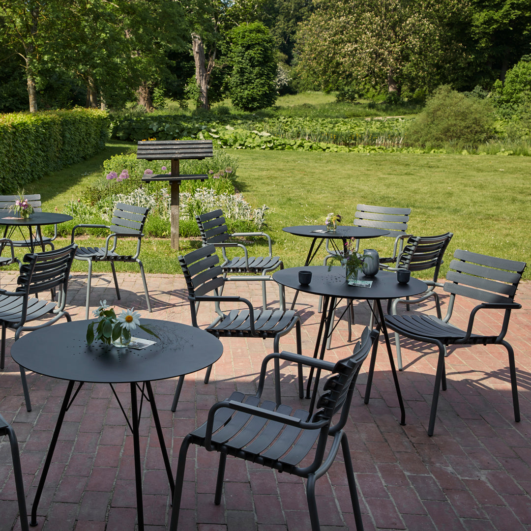 "Black striped patio furniture sets against a lush green garden backdrop, featuring simple modern design."