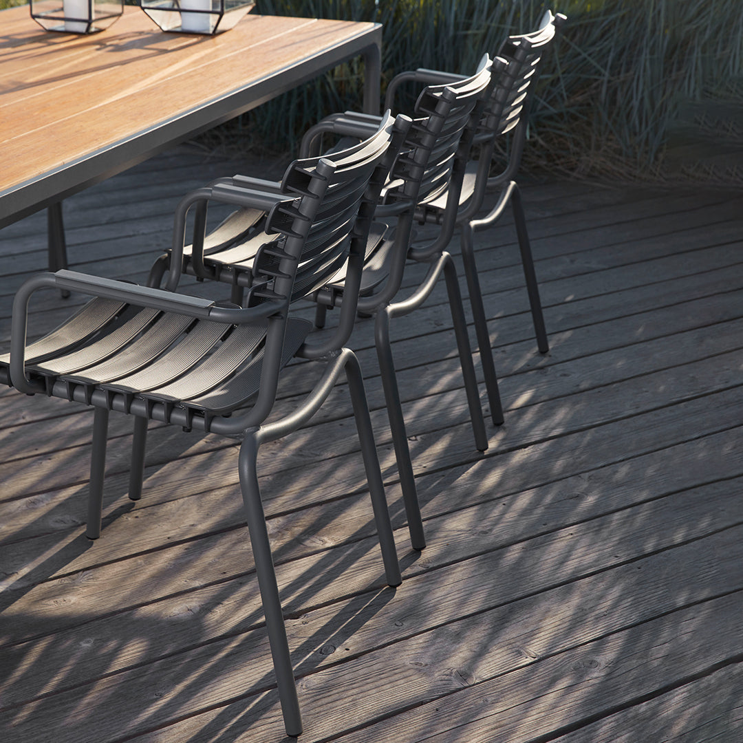 Black outdoor dining chairs with sleek, slatted design, paired with a natural wood tabletop against a deck background.