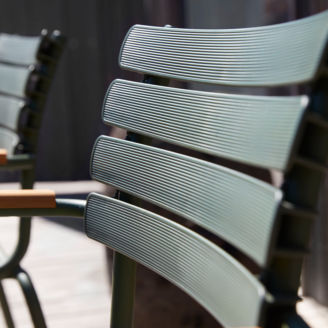 Close-up of textured, green chair slats with subtle grooves and a modern design, featuring natural wood accents.
