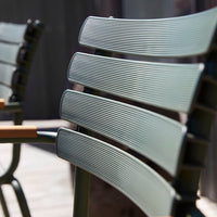 Close-up of textured, green chair slats with subtle grooves and a modern design, featuring natural wood accents.