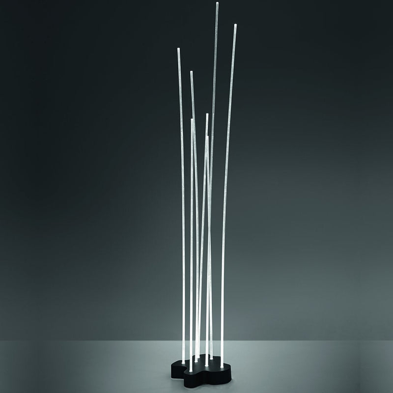 Modern floor lamp with sleek white LED rods on a black base, set against a dark backdrop.
