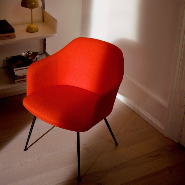 Vibrant orange upholstered chair with sleek black legs, showcasing a modern minimalist design.