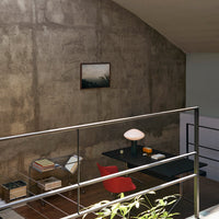 Modern interior featuring a red chair, black desk, and concrete wall, complemented by neutral tones and soft lighting.