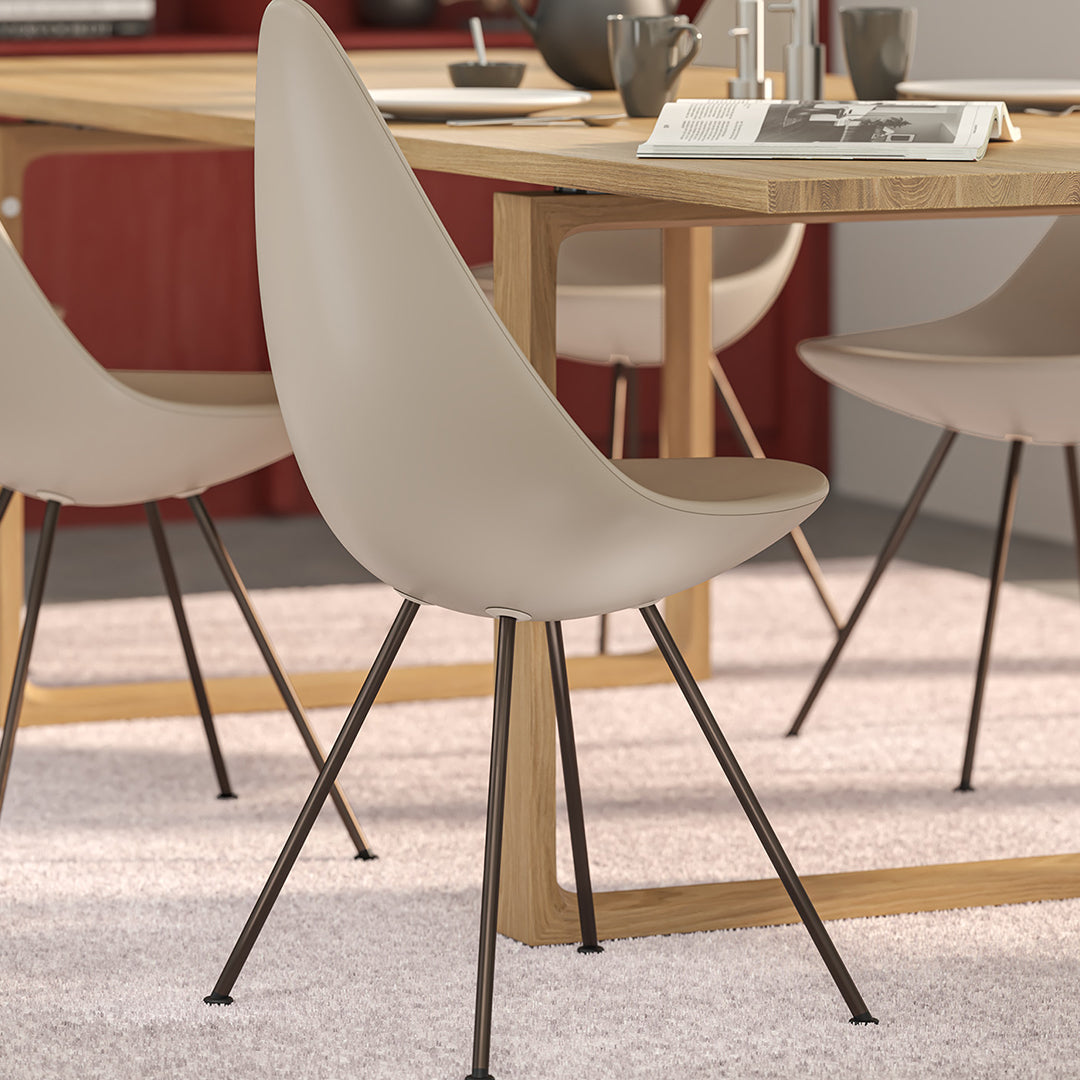 Beige dining chair with smooth curves and black metal legs, set against a warm-toned modern dining room backdrop.