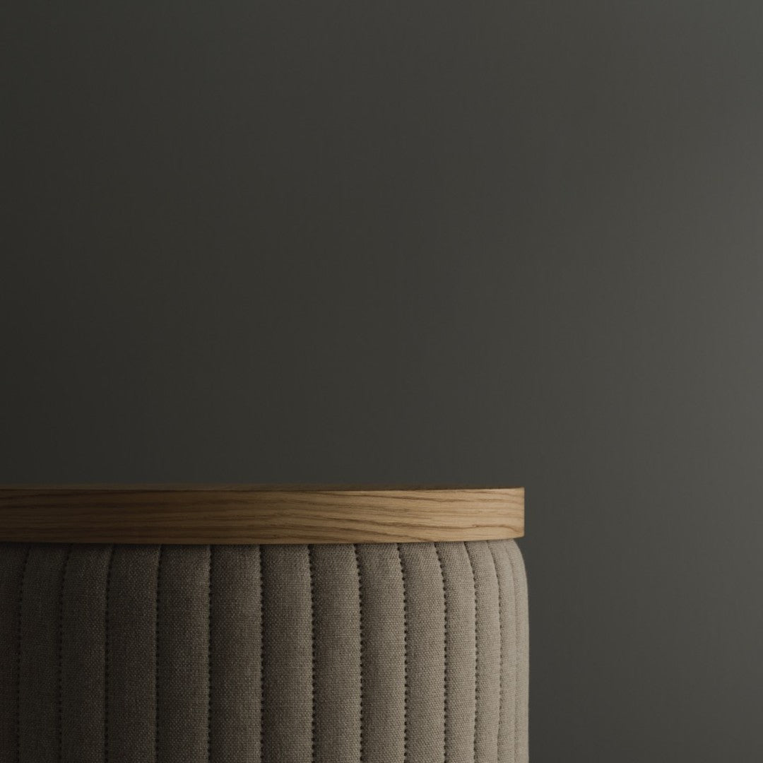 Gray tufted fabric with a light wood top against a dark background. Elegant and modern design.