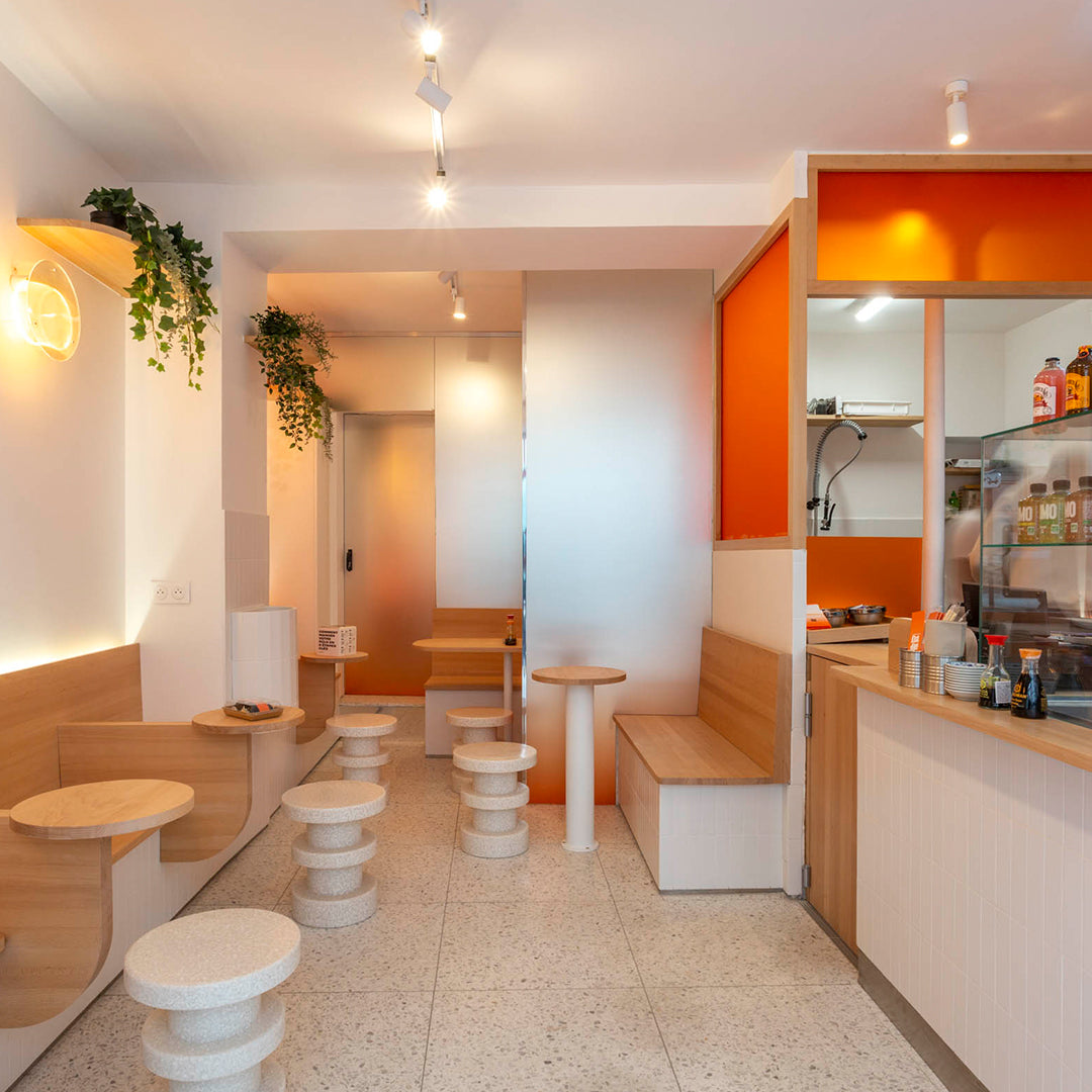 Bright white and warm wood tones, accented by vibrant orange walls; minimalist design with smooth, circular seating.