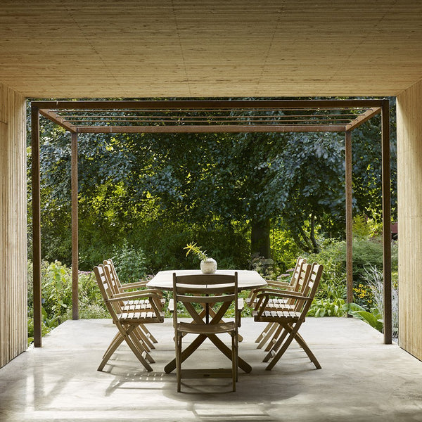 Outdoor dining set featuring natural wood tones and neutral shades, surrounded by lush green foliage.