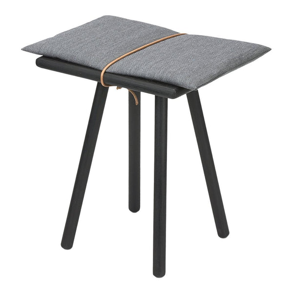 Gray cushion with simple pattern on a black wooden stool with slender legs and a decorative tan tie.