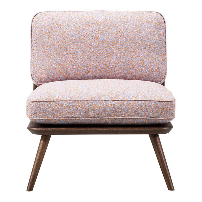 Light pink chair with a textured pattern of orange dots and a sleek, wooden base, exuding a modern retro style.