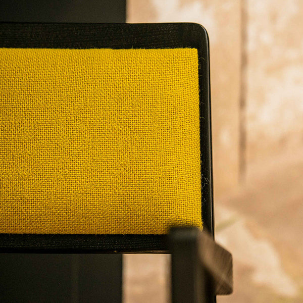 Close-up of a textured yellow chair seat with a black trim, showcasing a modern and vibrant color contrast.
