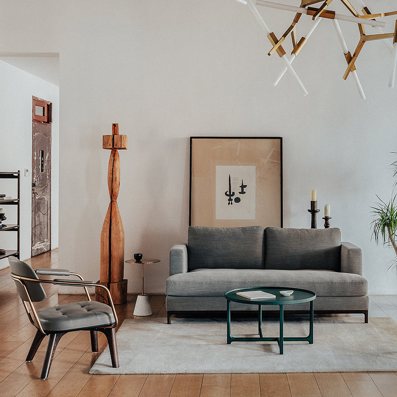 Gray sofa with a minimalist design, surrounded by warm wood tones and neutral beige accents; geometric patterns on accessories.