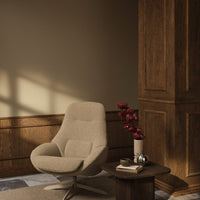 Beige textured chair with light gray cushions, dark wooden table, and warm brown walls. Elegant floral arrangement.