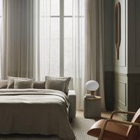 Neutral-toned bedding paired with soft beige curtains and light wooden accents in a cozy bedroom setting.