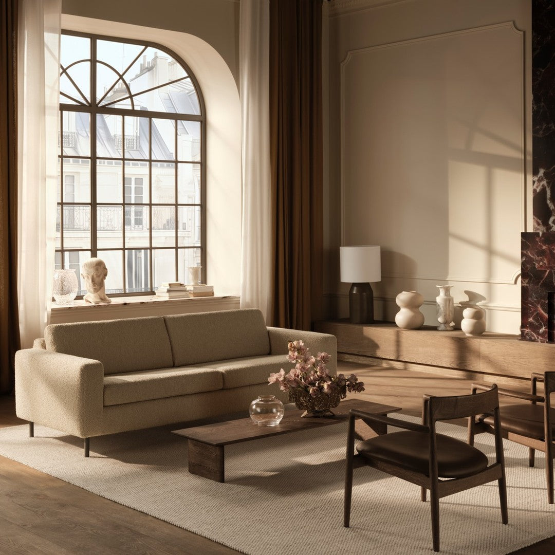 Light beige sofa, warm wooden accents, taupe curtains, and neutral tones create a cozy, modern living space.