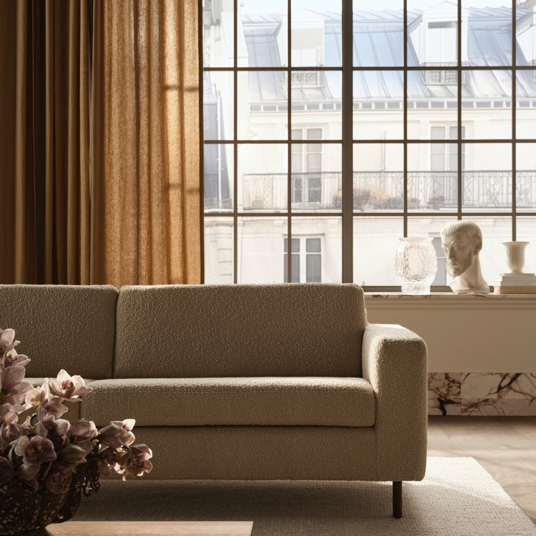 Cream-colored sofa with a textured fabric, paired with soft beige curtains and light natural tones in the room.