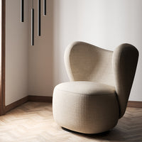 Beige upholstered chair with a modern, curved design and textured fabric, set against a light wall and wooden floor.