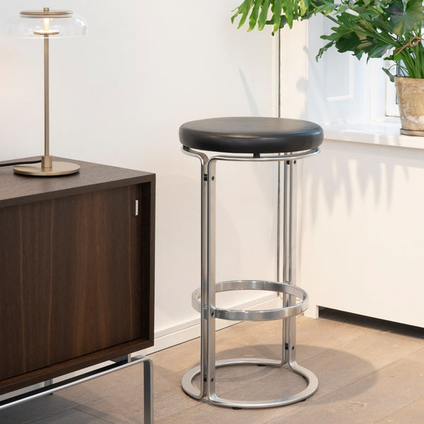 Black leather bar stool with sleek chrome accents in a modern interior setting. Perfect blend of elegance and style.