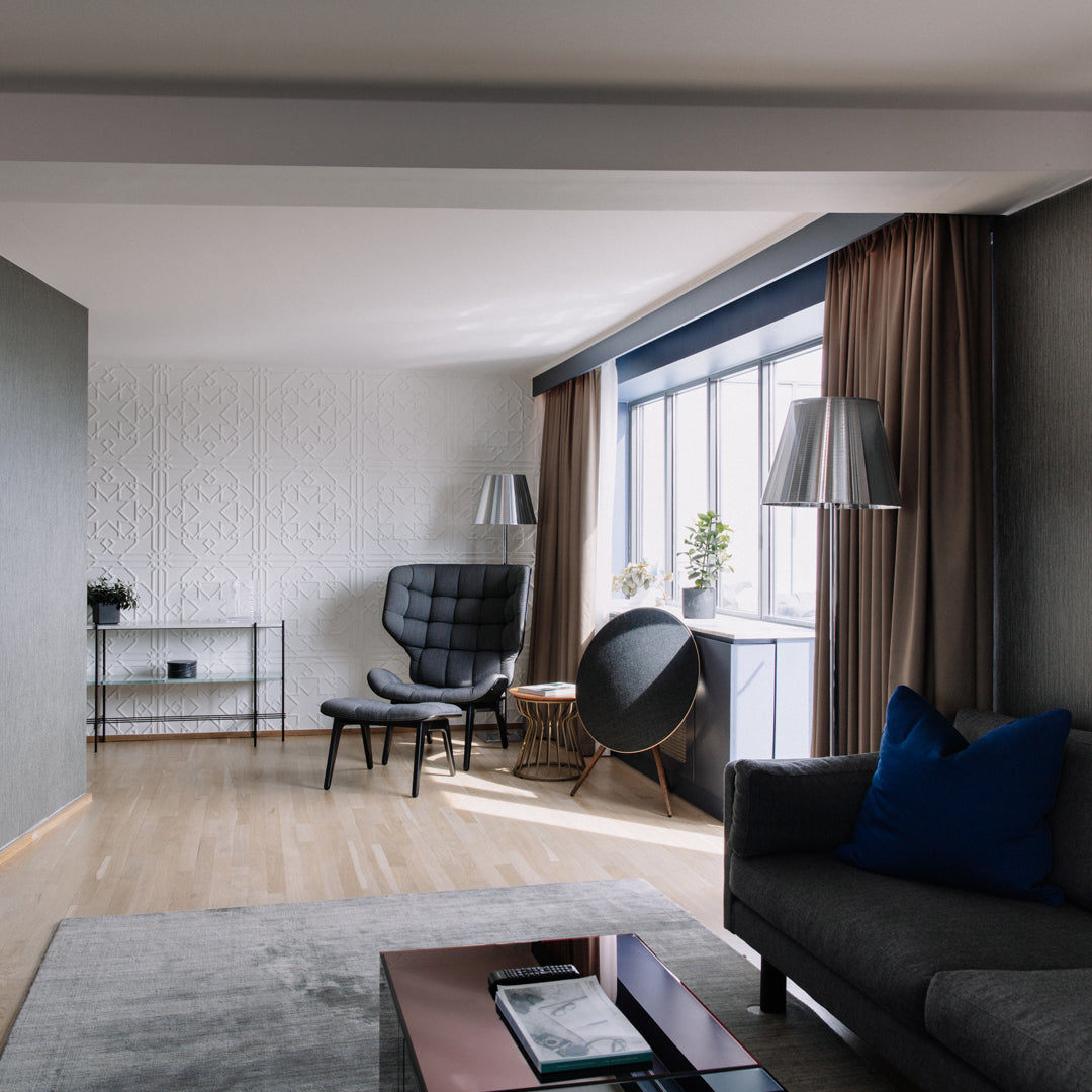 Modern living room featuring gray walls, beige curtains, a blue pillow, and stylish furniture in neutral tones.