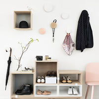 Neutral tones with black stripes, pastel pink accents, and subtle patterns enhance a modern entryway setting.
