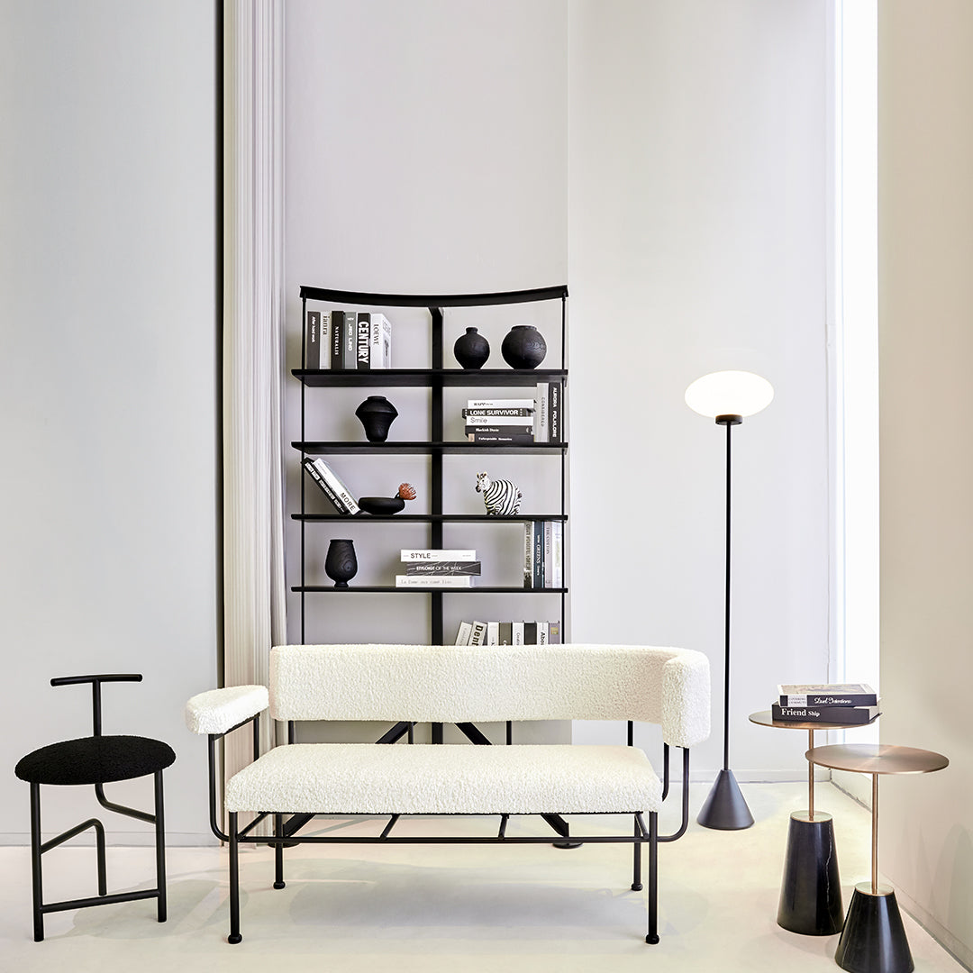 "Modern minimalist sofa in white fabric with black metal frame, paired with black furniture accents and neutral tones."