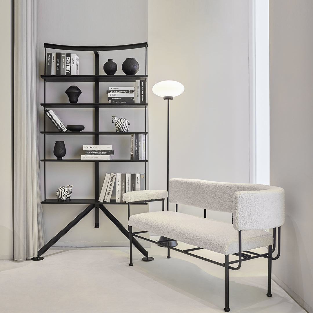Modern black metal shelf with white cushions, minimalist design, clean lines, and neutral color palette.